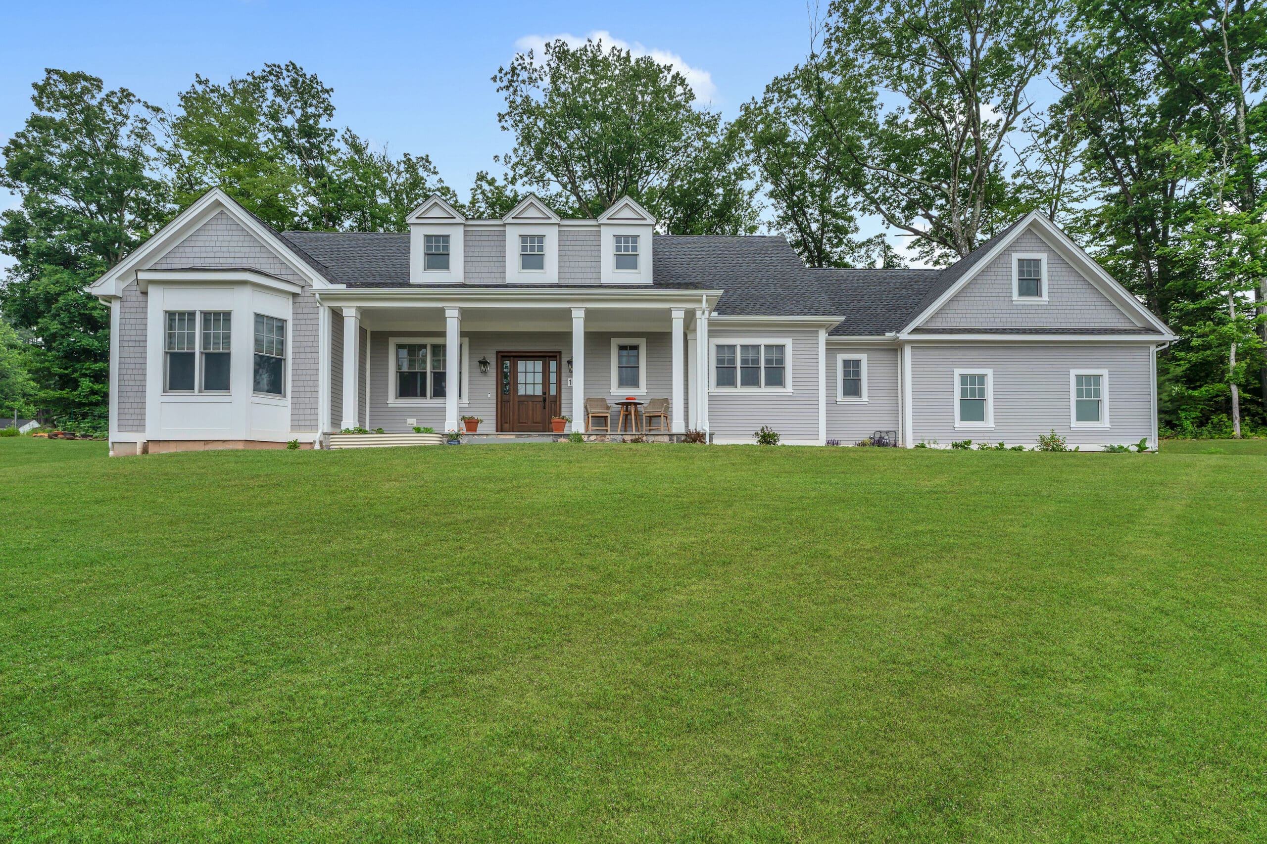 Single-story gray house with white trim, covered front porch, and large front lawn