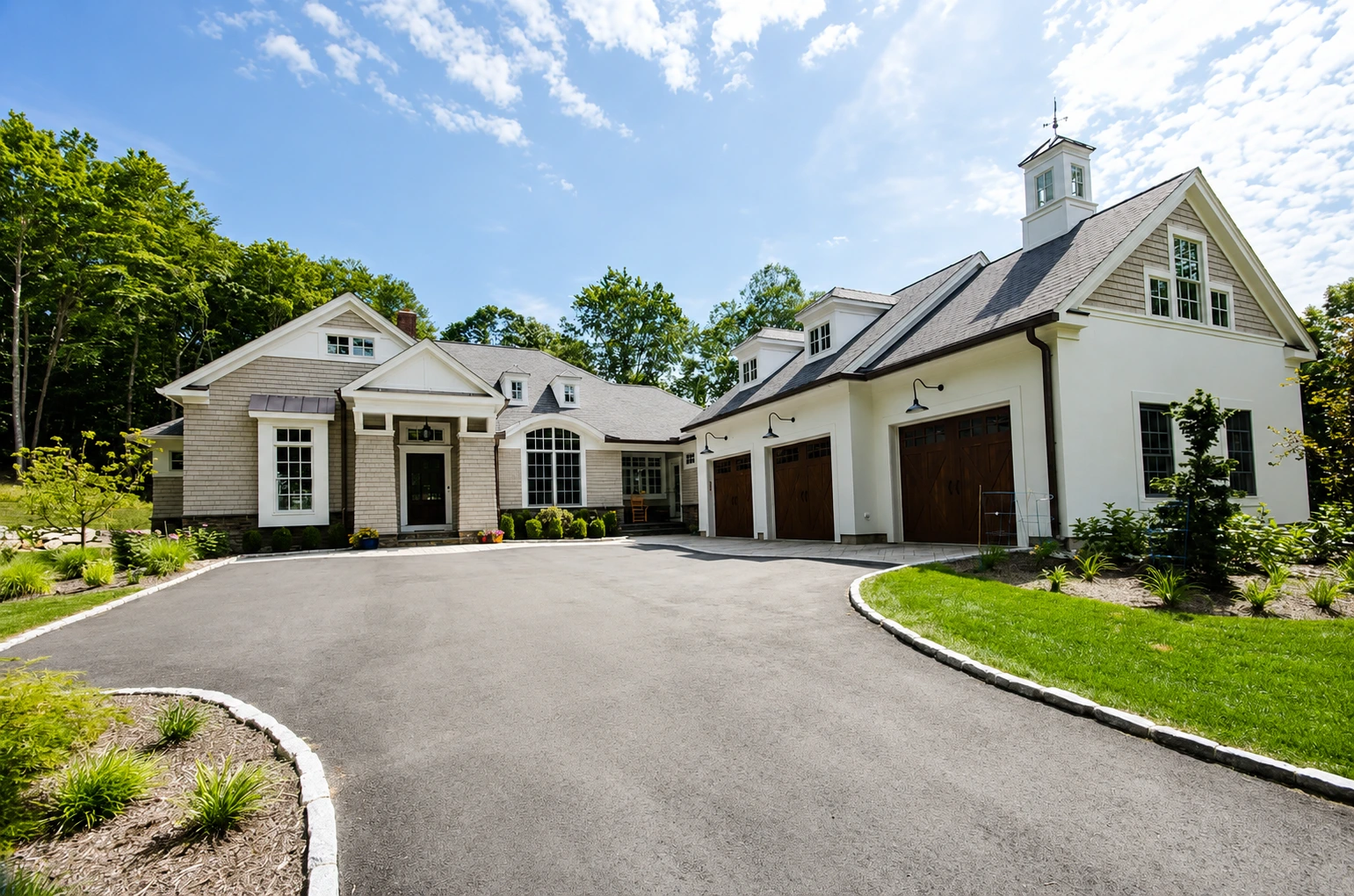 A large custom modern farmhouse with an asphalt driveway and multi-car garage in Connecticut